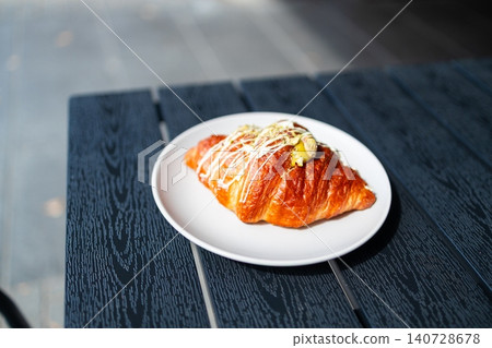 Savory breakfast croissant sandwich with scrambled egg and sauce close up Savory breakfast croissant sandwich with scrambled egg and sauce close up 140728678