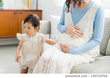 A pregnant mother holding her one-year-old daughter. A pregnant mother holding her one-year-old daughter. 140728708