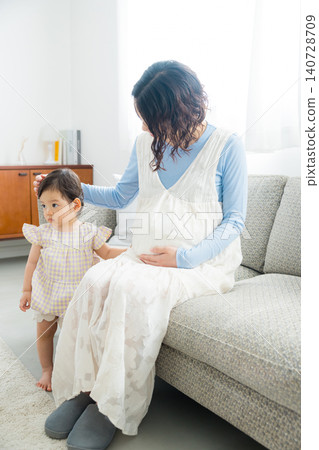 A pregnant mother holding her one-year-old daughter. A pregnant mother holding her one-year-old daughter. 140728709