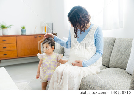 A pregnant mother holding her one-year-old daughter. A pregnant mother holding her one-year-old daughter. 140728710