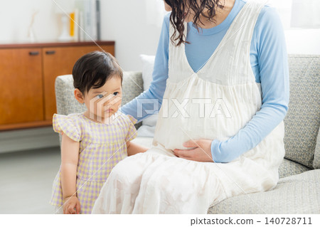 A pregnant mother holding her one-year-old daughter. A pregnant mother holding her one-year-old daughter. 140728711