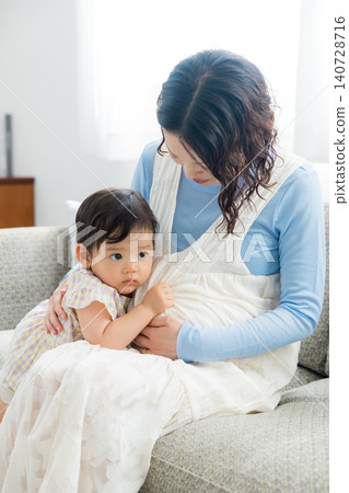一位懷孕的母親抱著她一歲的女兒。 140728716
