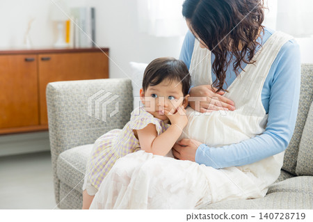 一位懷孕的母親抱著她一歲的女兒。 一位懷孕的母親抱著她一歲的女兒。 140728719