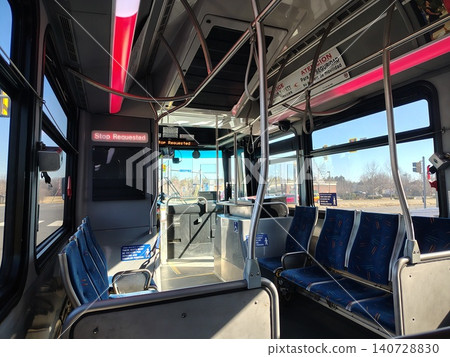 Washington, DC, USA - March 3, 2025: Rows of blue fabric seats with information signs inside a deserted bus. The street is visible through the large side windows and windshield on a clear sunny day. Washington, DC, USA - March 3, 2025: Rows of blue fabric seats with information signs inside a deserted bus. The street is visible through the large side windows and windshield on a clear sunny day. 140728830