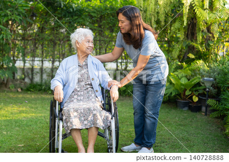 Caregiver help Asian elderly woman disability patient sitting on wheelchair in park. Caregiver help Asian elderly woman disability patient sitting on wheelchair in park. 140728888