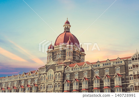 Mumbai Maharashtra India Jan 18 2026 Architectural detail of the iconic red central dome and Victorian Gothic facade of the Taj Mahal Palace Hotel during a vibrant sunset with a colorful orange and pu Mumbai Maharashtra India Jan 18 2026 Architectural detail of the iconic red central dome and Victorian Gothic facade of the Taj Mahal Palace Hotel during a vibrant sunset with a colorful orange and pu 140728991