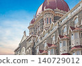 Mumbai Maharashtra India Jan 18 2026 Ornate red domes and grey stone architectural details of the historic Taj Mahal Palace Hotel building against a bright blue sky in South Mumbai 140729012