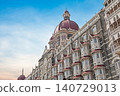 Mumbai Maharashtra India Jan 18 2026 Ornate red domes and grey stone architectural details of the historic Taj Mahal Palace Hotel building against a bright blue sky in South Mumbai 140729013