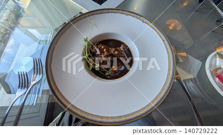 Braised rabbit liver in a dark brown sauce served on a white round plate Braised rabbit liver in a dark brown sauce served on a white round plate 140729222
