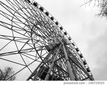 Ferris wheel rises with dark mood creating dramatic scene. Large structure appears ominous against sky forming horror style composition. Ferris wheel rises with dark mood creating dramatic scene. Large structure appears ominous against sky forming horror style composition. 140729583
