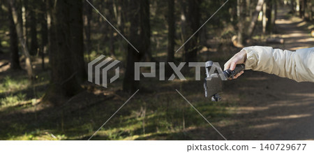 Smartphone on a gimbal in a forest. Handheld mobile filming gear on a woodland trail. Outdoor videography and vlogging setup.. Smartphone on a gimbal in a forest. Handheld mobile filming gear on a woodland trail. Outdoor videography and vlogging setup.. 140729677
