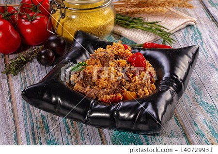 Couscous with beef and vegetables in modern black bowl on rustic table Couscous with beef and vegetables in modern black bowl on rustic table 140729931
