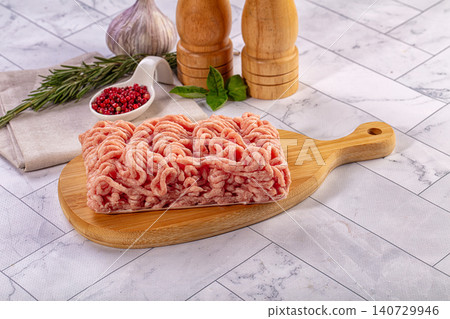 Raw ground chicken or turkey meat on wooden cutting board with spices Raw ground chicken or turkey meat on wooden cutting board with spices 140729946