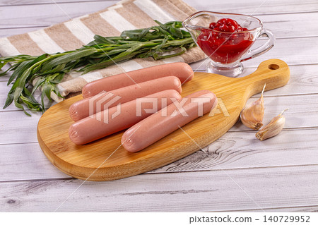 Fresh sausages on wooden board with tomato sauce, garlic, and tarragon Fresh sausages on wooden board with tomato sauce, garlic, and tarragon 140729952