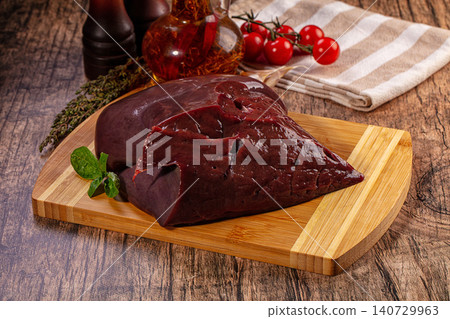 Raw liver on wooden cutting board with fresh herbs and tomatoes for cooking Raw liver on wooden cutting board with fresh herbs and tomatoes for cooking 140729963