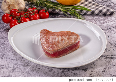Gourmet seared tuna steak on white plate with fresh tomatoes and herbs 140729971