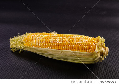Fresh yellow corn cob with husk on black background Fresh yellow corn cob with husk on black background 140729995
