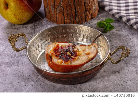 Baked pear half with caramelized topping and nuts in vintage metal bowl 140730016