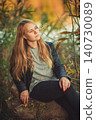 Contemplative blonde woman in leather jacket relaxing outdoors in autumn park 140730089