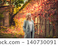 Blonde woman in gray coat, autumn park, vibrant foliage background 140730091