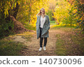Smiling blonde woman walking autumn park path, vibrant yellow foliage 140730096