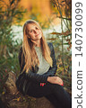 Portrait of smiling young woman in black leather jacket enjoying autumn nature 140730099