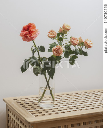Bouquet of garden roses in glass vase on table in interior space. Fresh flowers with leaves arranged in decorative composition with natural look. Concept of home decor floral arrangement.. 140730266