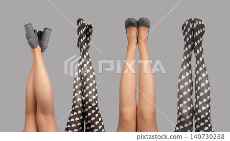 Female legs raised upward wearing heels and patterned tights isolated white background. Woman limbs lifted vertically in playful hosiery and shoes against clean backdrop. Concept of fashion Female legs raised upward wearing heels and patterned tights isolated white background. Woman limbs lifted vertically in playful hosiery and shoes against clean backdrop. Concept of fashion 140730288