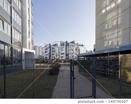 Gated residential complex with fence and entrance gate in urban courtyard. Modern housing area shows secured territory and enclosed space. Concept of privacy safety property management.. Gated residential complex with fence and entrance gate in urban courtyard. Modern housing area shows secured territory and enclosed space. Concept of privacy safety property management.. 140730307