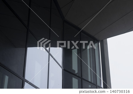 Glass facade detail with reflections and modern architectural lines. Transparent surface creates geometric composition and urban aesthetic. Concept of contemporary design exterior.. Glass facade detail with reflections and modern architectural lines. Transparent surface creates geometric composition and urban aesthetic. Concept of contemporary design exterior.. 140730316