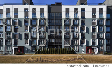 Modern residential buildings forming symmetrical urban composition with clean facade lines. Apartment structures show geometric design and contemporary style Modern residential buildings forming symmetrical urban composition with clean facade lines. Apartment structures show geometric design and contemporary style 140730365