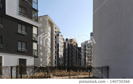 Modern residential buildings seen through narrow urban space between structures. Architectural composition shows perspective and depth in city environment. Concept of contemporary housing Modern residential buildings seen through narrow urban space between structures. Architectural composition shows perspective and depth in city environment. Concept of contemporary housing 140730366