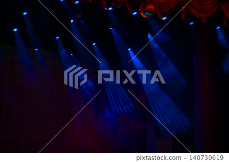 Set of professional stage lighting equipment on the stage for gig illumination of theater or concert hall. Stage lights, spotlights and laser beams. Rays of light from the floodlights. Concert light. Set of professional stage lighting equipment on the stage for gig illumination of theater or concert hall. Stage lights, spotlights and laser beams. Rays of light from the floodlights. Concert light. 140730619