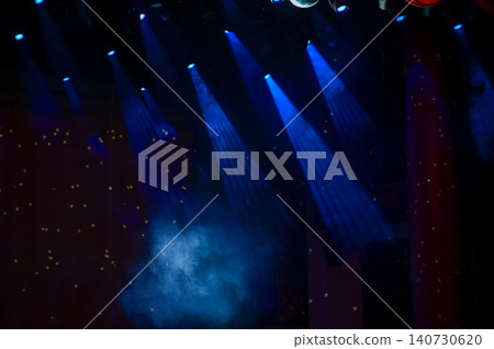 Set of professional stage lighting equipment on the stage for gig illumination of theater or concert hall. Stage lights, spotlights and laser beams. Rays of light from the floodlights. Concert light. Set of professional stage lighting equipment on the stage for gig illumination of theater or concert hall. Stage lights, spotlights and laser beams. Rays of light from the floodlights. Concert light. 140730620