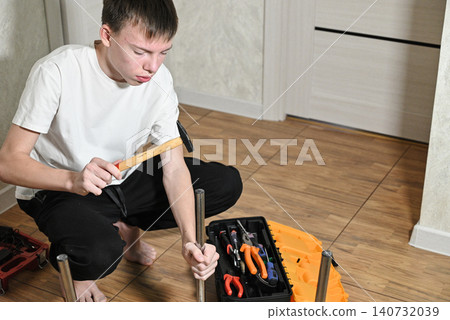 Young working man repairing wooden stool using screwdriver indoors, closeup Young working man repairing wooden stool using screwdriver indoors, closeup 140732039