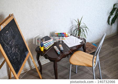 Creative workspace features painting supplies, brushes, and colorful materials ready for an art project at a desk Creative workspace features painting supplies, brushes, and colorful materials ready for an art project at a desk 140732066