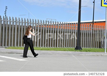 Woman walking near a retractable barrier with a modern building in the background. Woman walking near a retractable barrier with a modern building in the background. 140732328