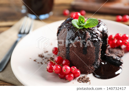 Delicious warm chocolate lava cake with mint and berries on plate, closeup Delicious warm chocolate lava cake with mint and berries on plate, closeup 140732417