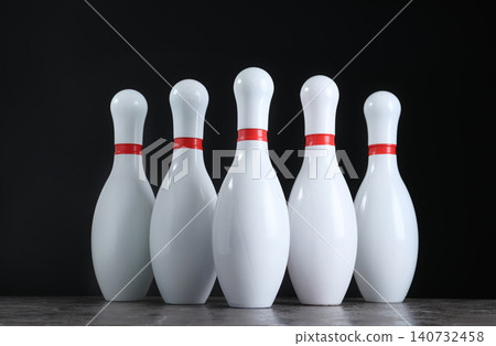 Set of bowling pins on grey stone table Set of bowling pins on grey stone table 140732458