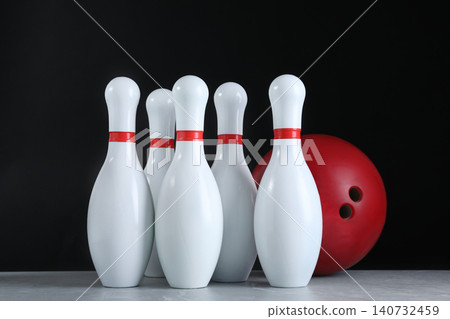 Red bowling ball and pins on grey stone table 140732459