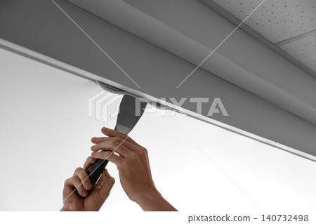Repairman installing white stretch ceiling in room, closeup Repairman installing white stretch ceiling in room, closeup 140732498