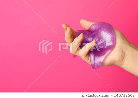 Woman playing with purple slime on pink background, closeup. Antistress toy Woman playing with purple slime on pink background, closeup. Antistress toy 140732502