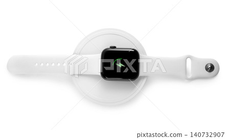 Smartwatch charging with wireless pad isolated on white, top view 140732907