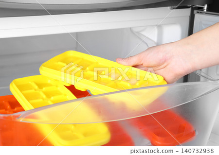 Woman taking tray with ice cubes from fridge, closeup Woman taking tray with ice cubes from fridge, closeup 140732938