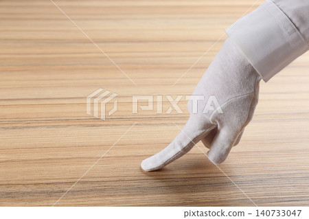 Person in white glove checking cleanliness of wooden table, closeup. Space for text Person in white glove checking cleanliness of wooden table, closeup. Space for text 140733047