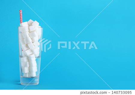 Refined sugar cubes in glass with straw on light blue background. Space for text Refined sugar cubes in glass with straw on light blue background. Space for text 140733095