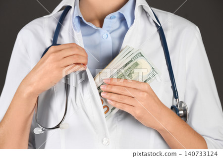 Doctor putting bribe into pocket on black background, closeup. Corruption in medicine 140733124
