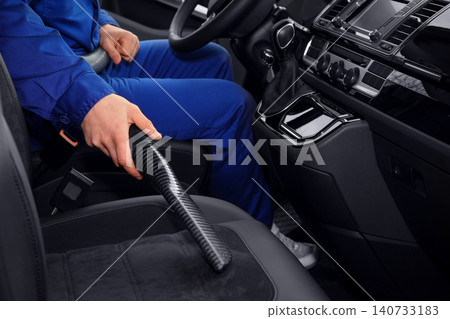 Car wash worker vacuuming automobile seat, closeup Car wash worker vacuuming automobile seat, closeup 140733183