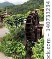 A wooden watermill and beautiful natural scenery nestled in a mountain village surrounded by fresh greenery. 140733234