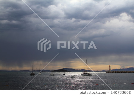 Seascape at sunshine. Lighthouse and sailings on the coast. Seaside town of Turgutreis and spectacular sunshine Seascape at sunshine. Lighthouse and sailings on the coast. Seaside town of Turgutreis and spectacular sunshine 140733608